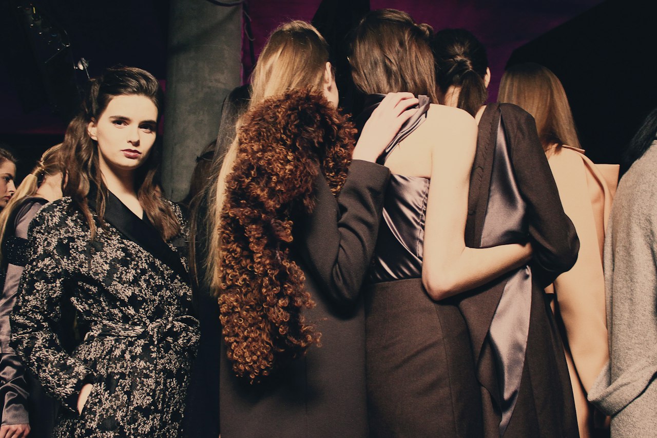 Models in tailored coats and silk waiting backstage before a show