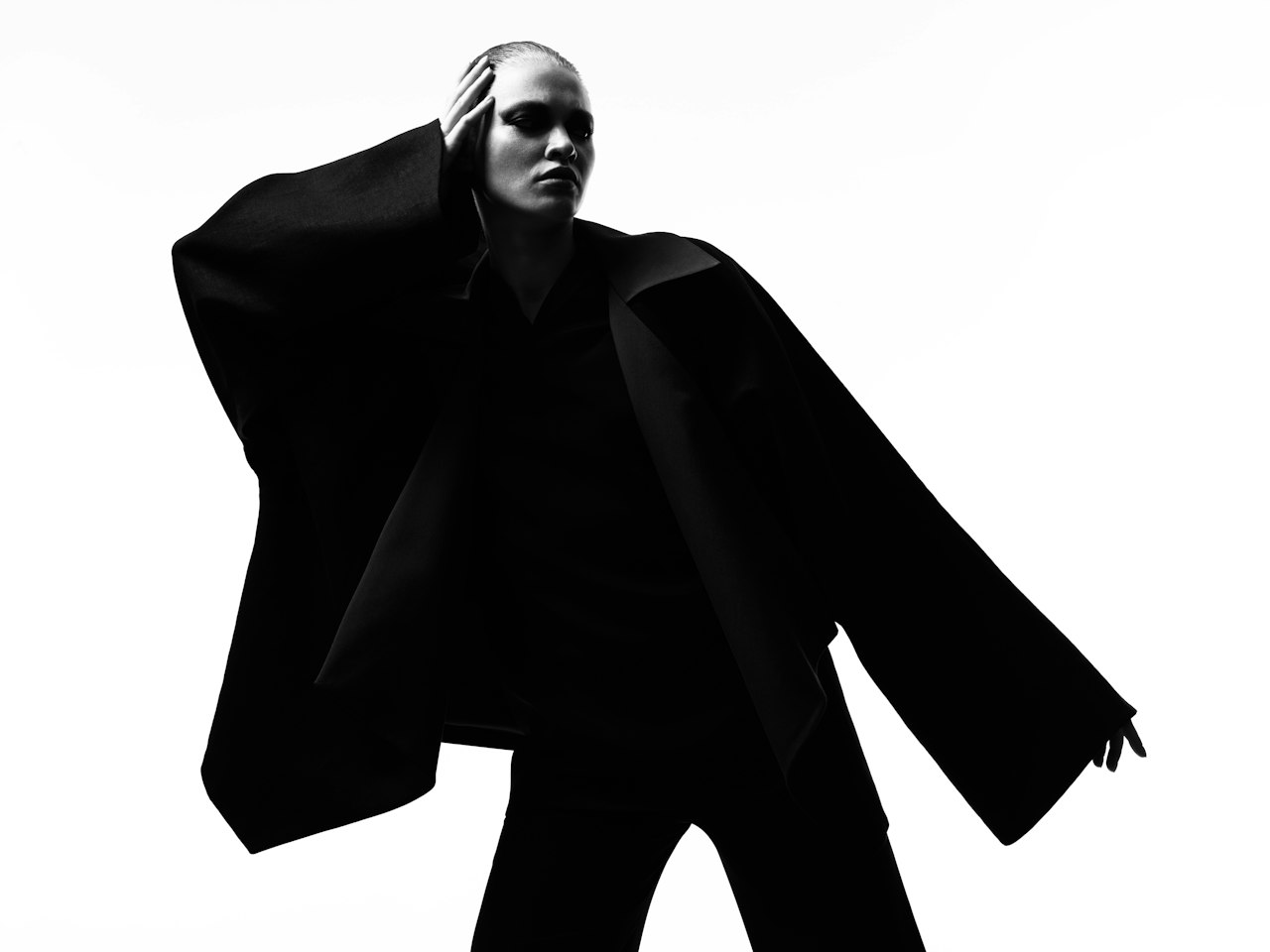 A figure in a wide-sleeved black coat against a white background